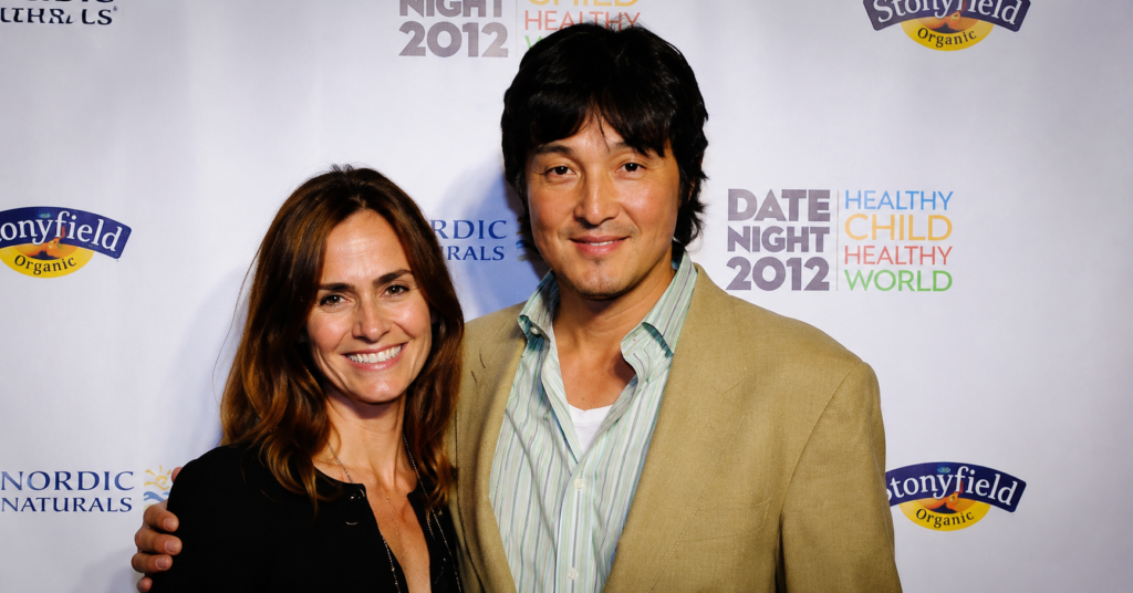 Seung Yong Chung and Diane Farr posing together on a red carpet event backdrop during a Hollywood charity event in 2012.