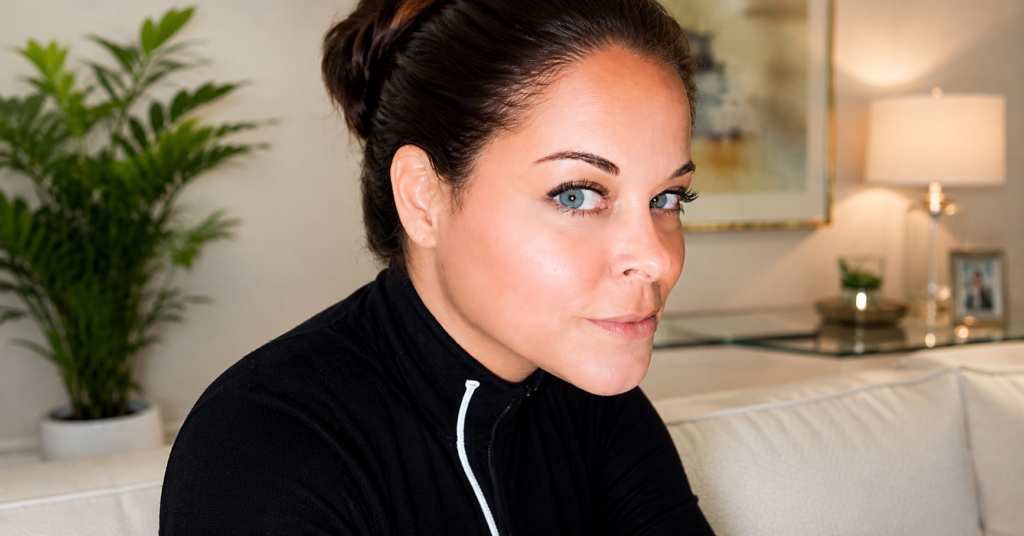 High-resolution portrait of Kari Hillsman sitting indoors with a modern blurred background, natural lighting, and a calm, confident expression.