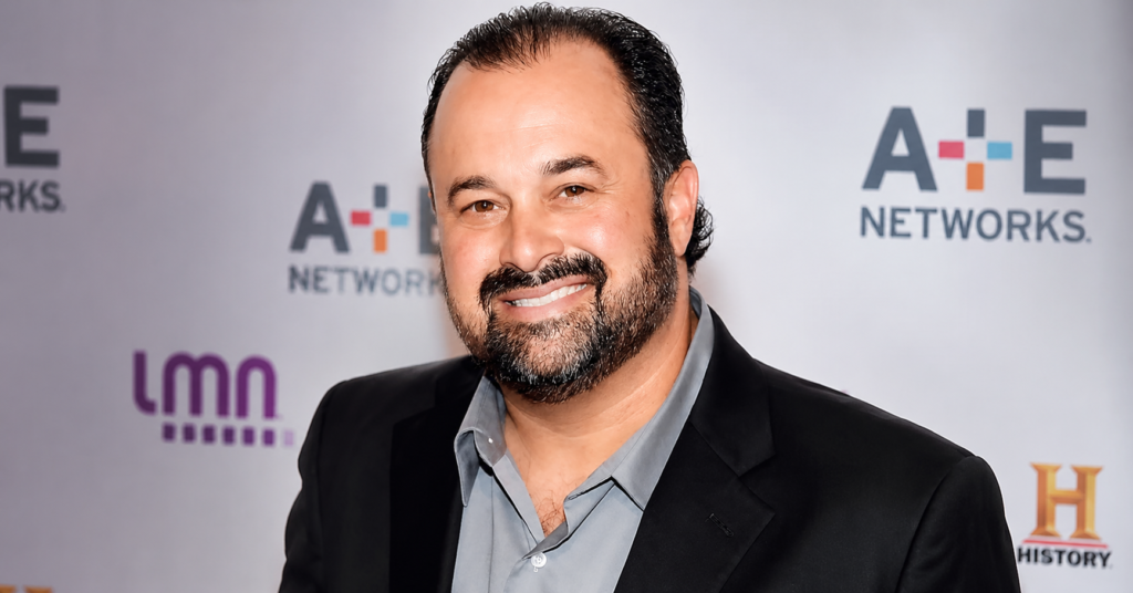 Portrait of Frank Fritz with a beard, smiling in a black blazer and gray shirt at an A+E Networks red carpet event.