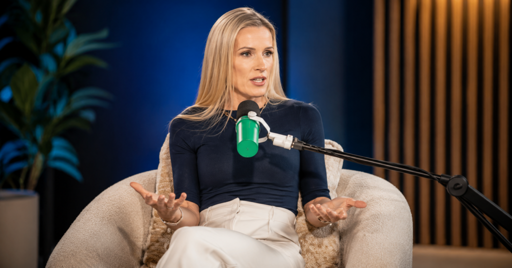 Kristin Cabot seated in a chair speaking into a microphone during a podcast interview while gesturing with her hands.