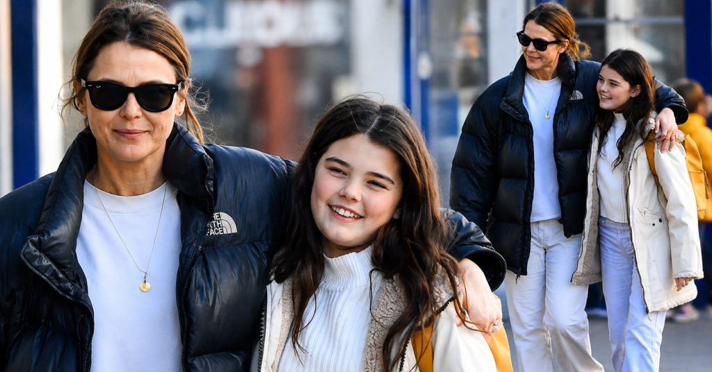 River Russell Deary smiles while walking alongside a family member during a daytime outing on a city street.