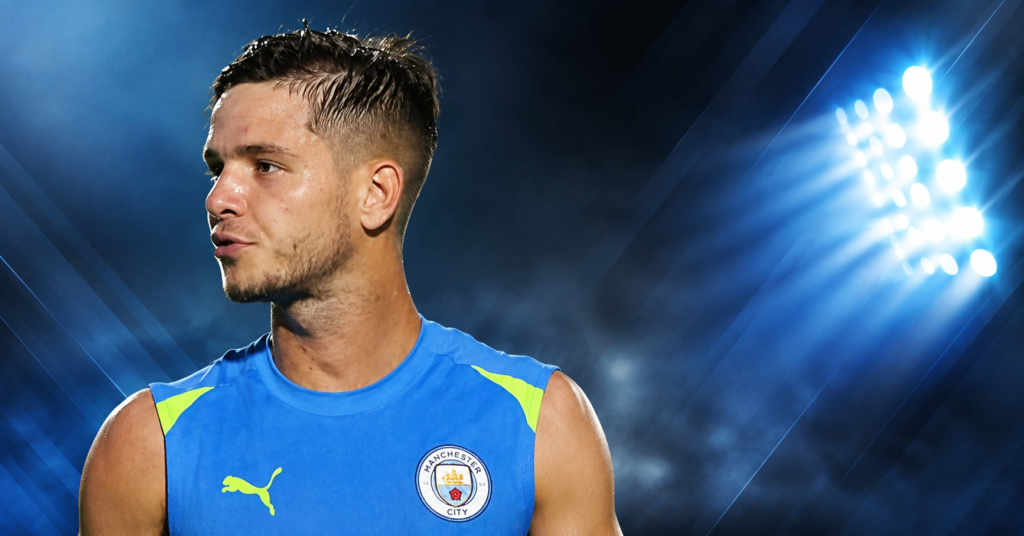 James McAtee in a Manchester City training jersey during a football training session, looking to the side on the pitch.